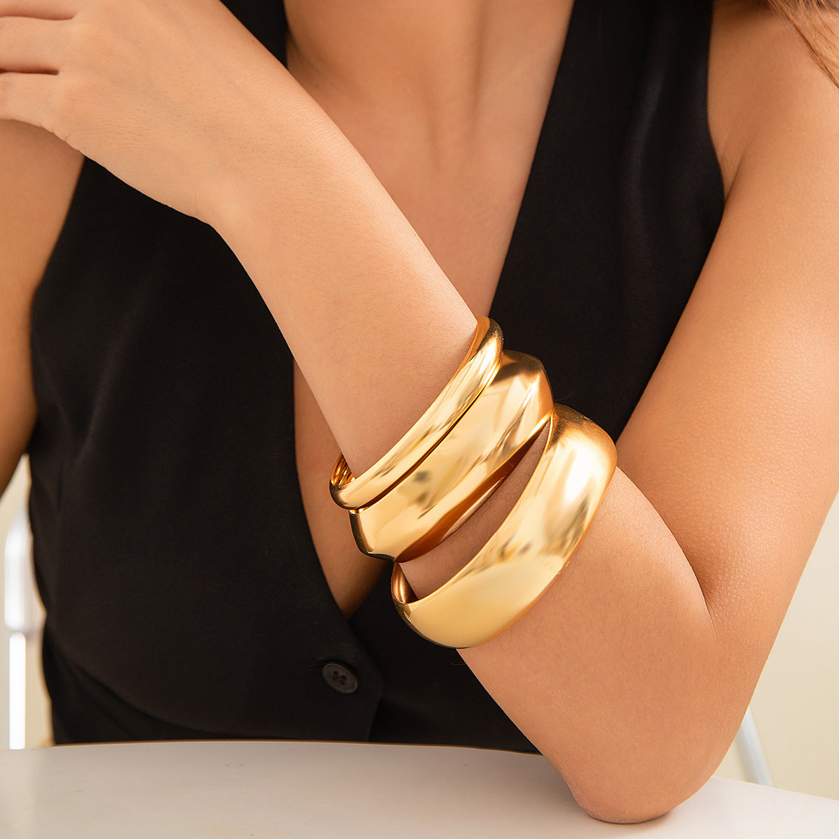 Gold bracelet on a person's wrist with a neutral background